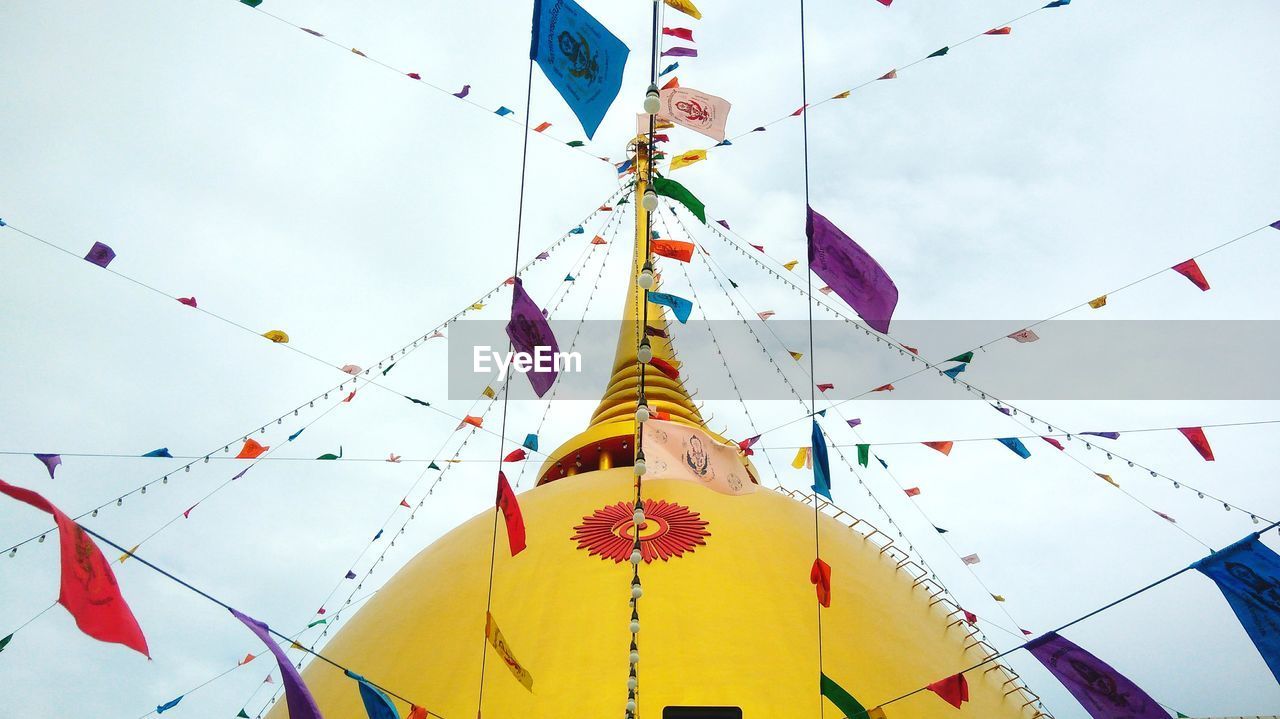 Low angle view of colorful flags decorated on temple against sky