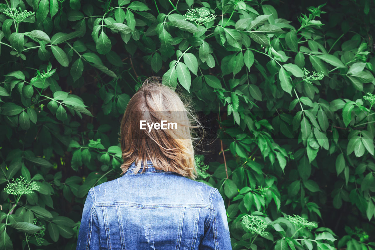 Rear view of woman standing by plants at park