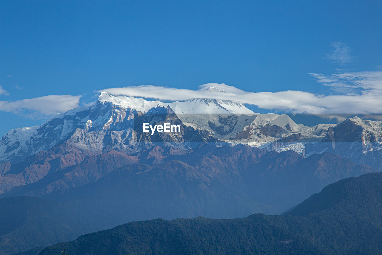 Scenic view of snowcapped mountains against blue sky