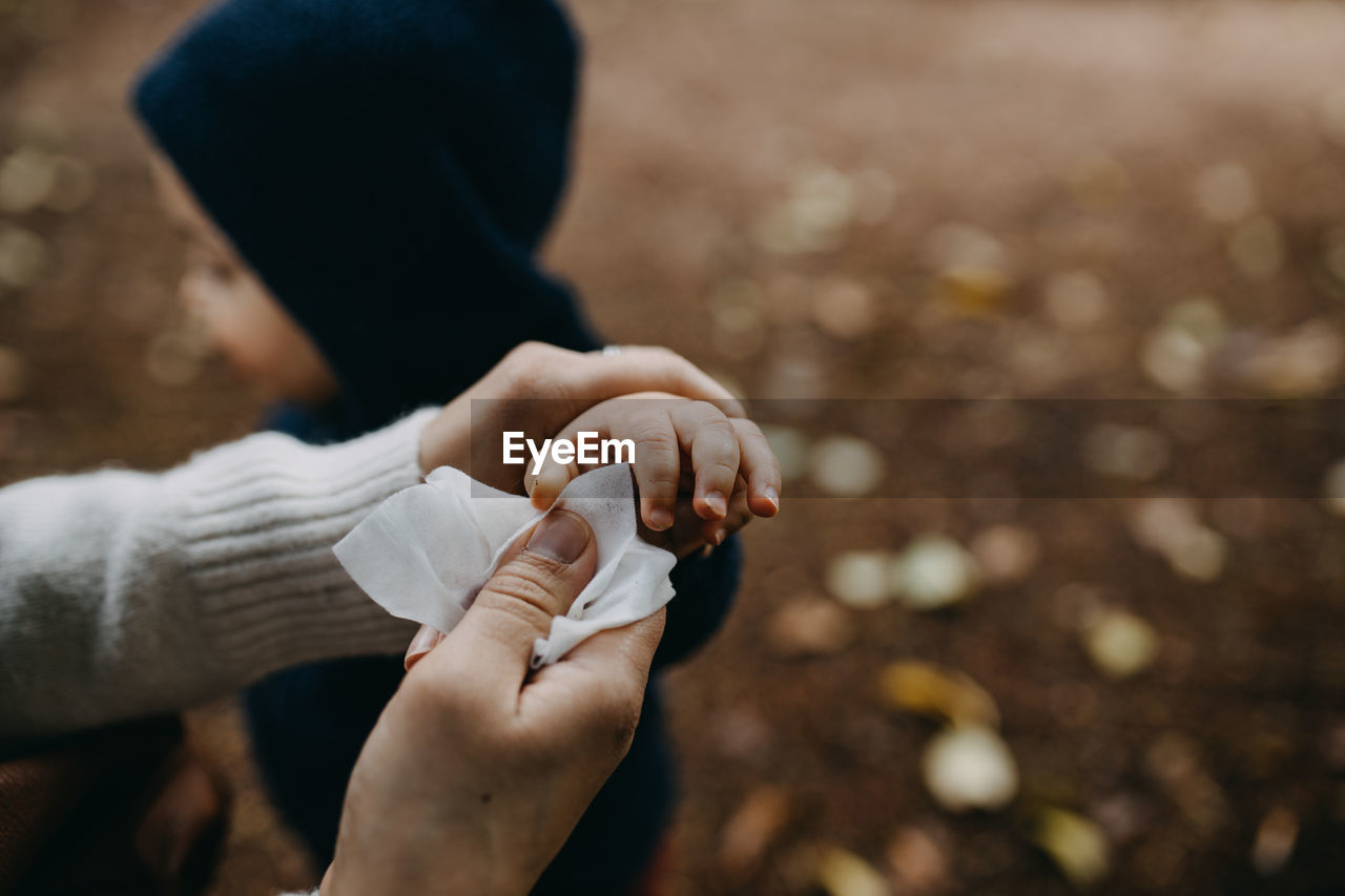 Woman cleaning son's hand with cloth