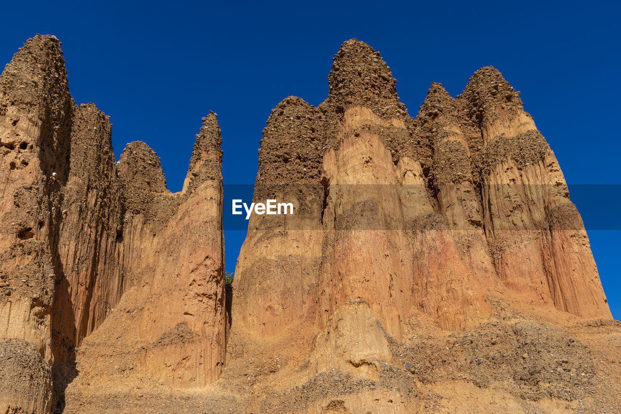 Low angle view of rock formations against blue sky