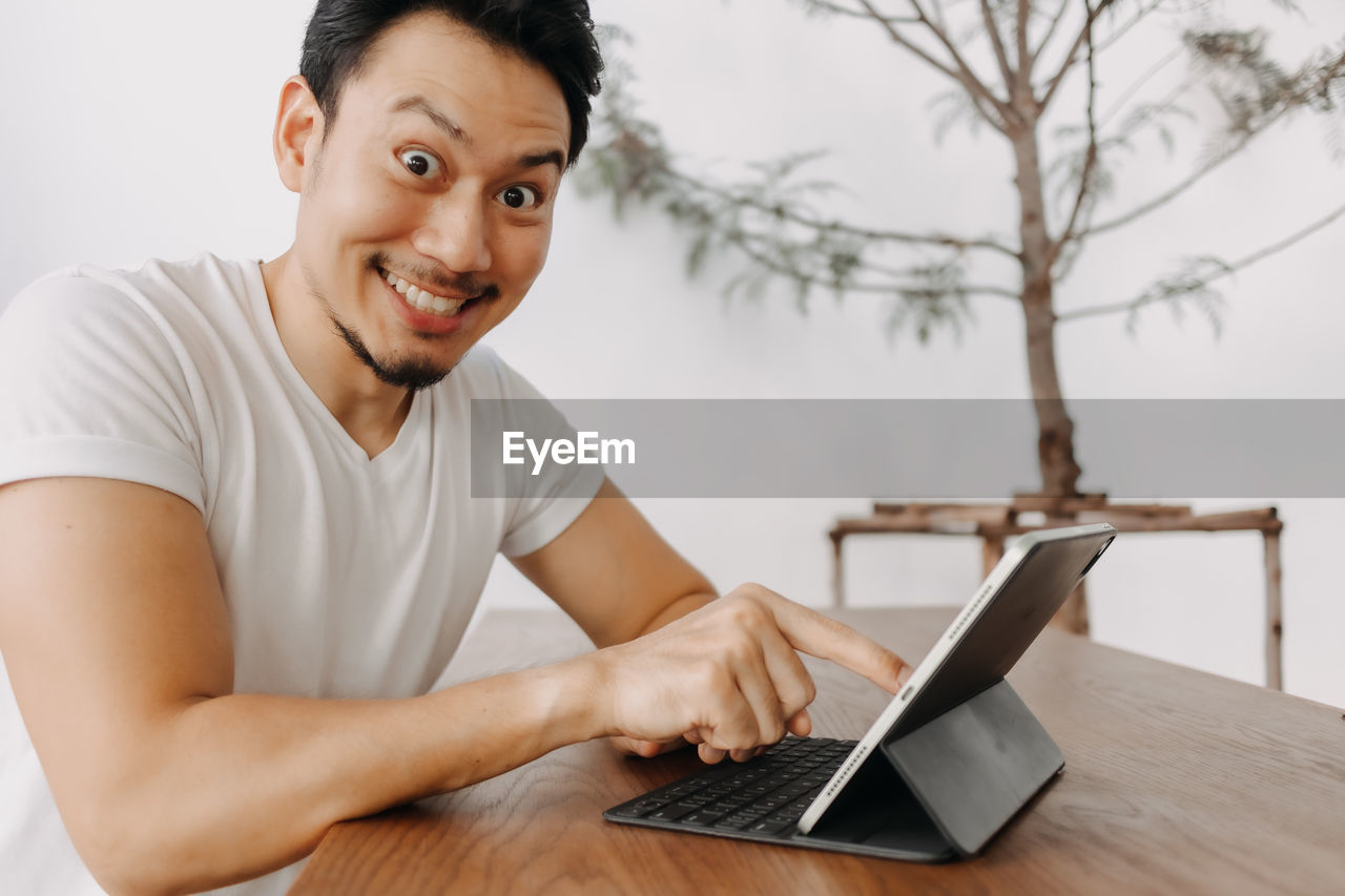 Portrait of smiling man using digital tablet at home