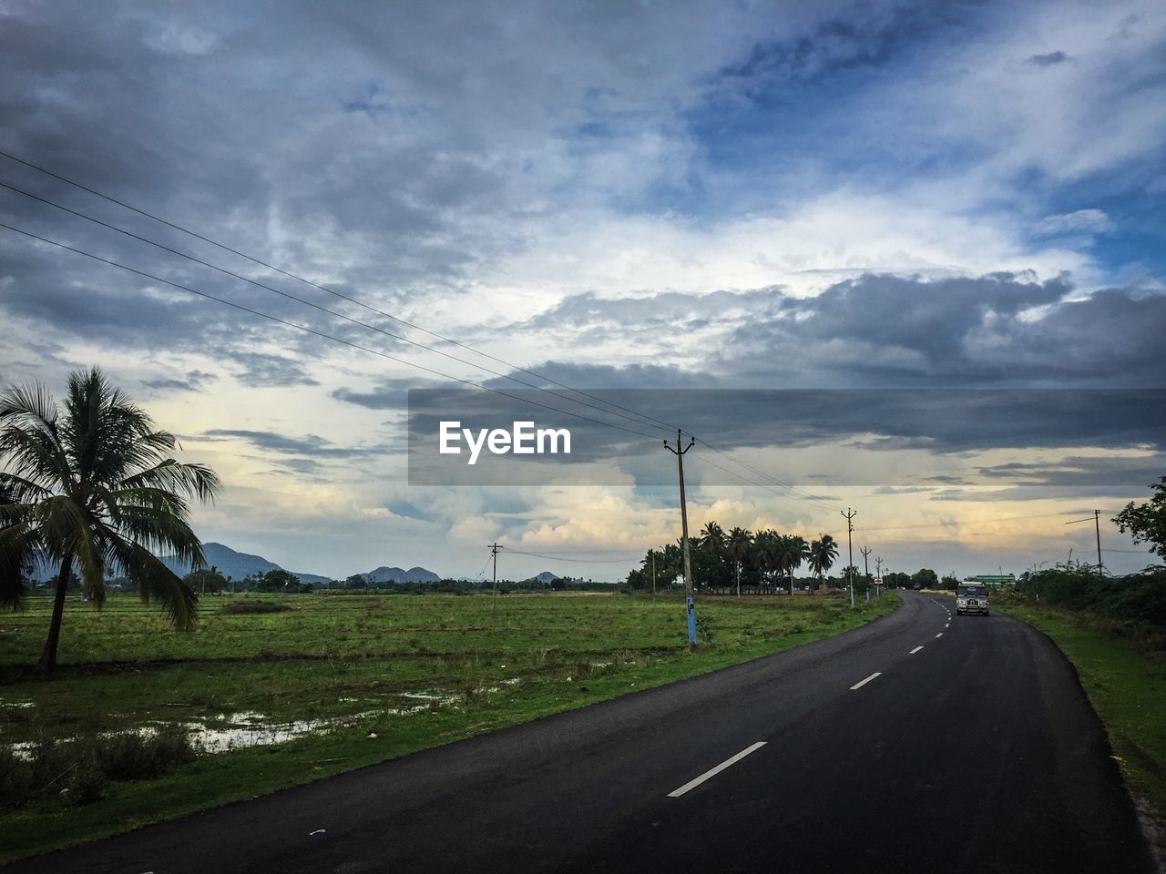 EMPTY ROAD WITH CLOUDY SKY IN BACKGROUND