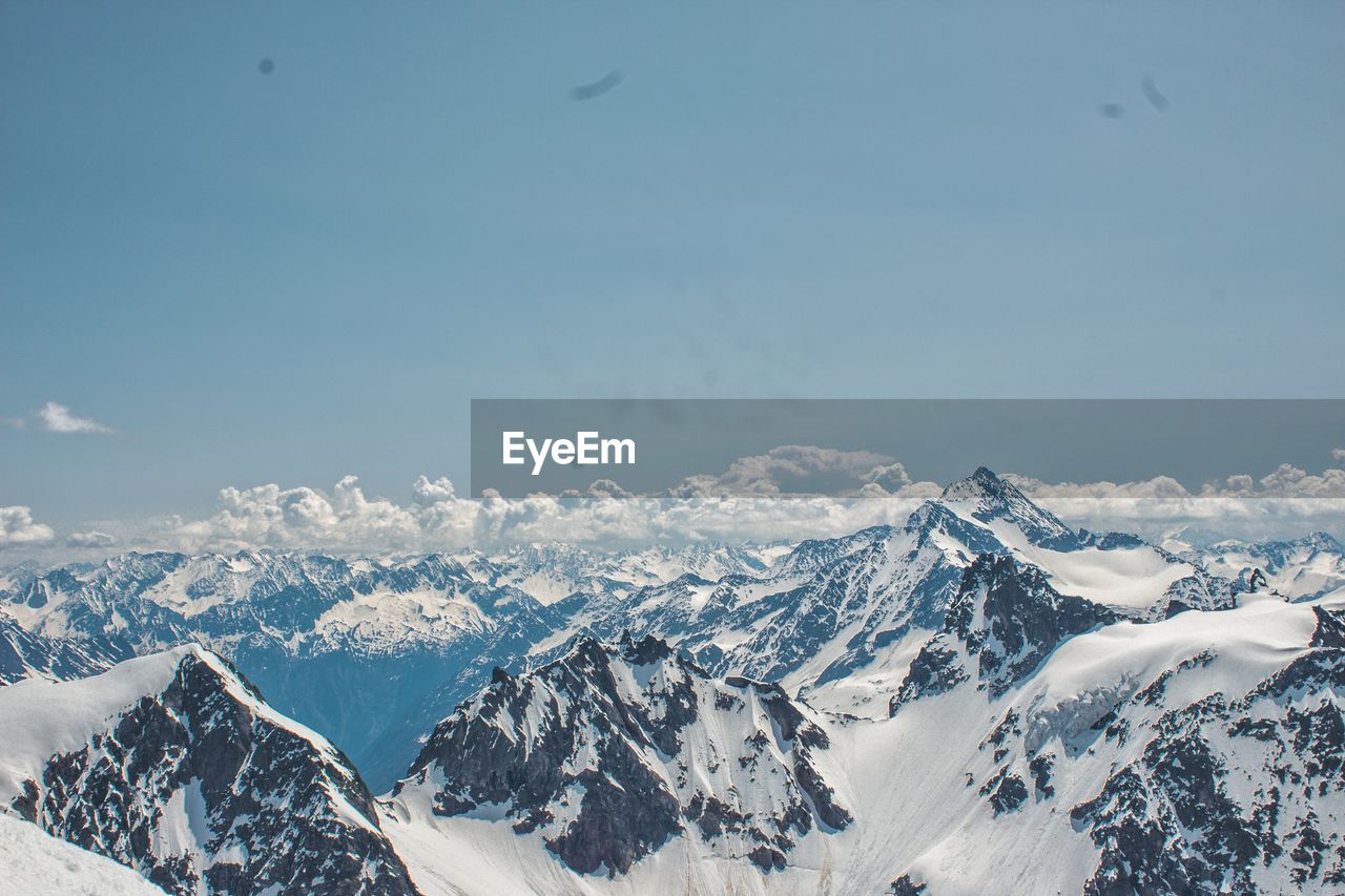 Scenic view of snowcapped mountains against blue sky