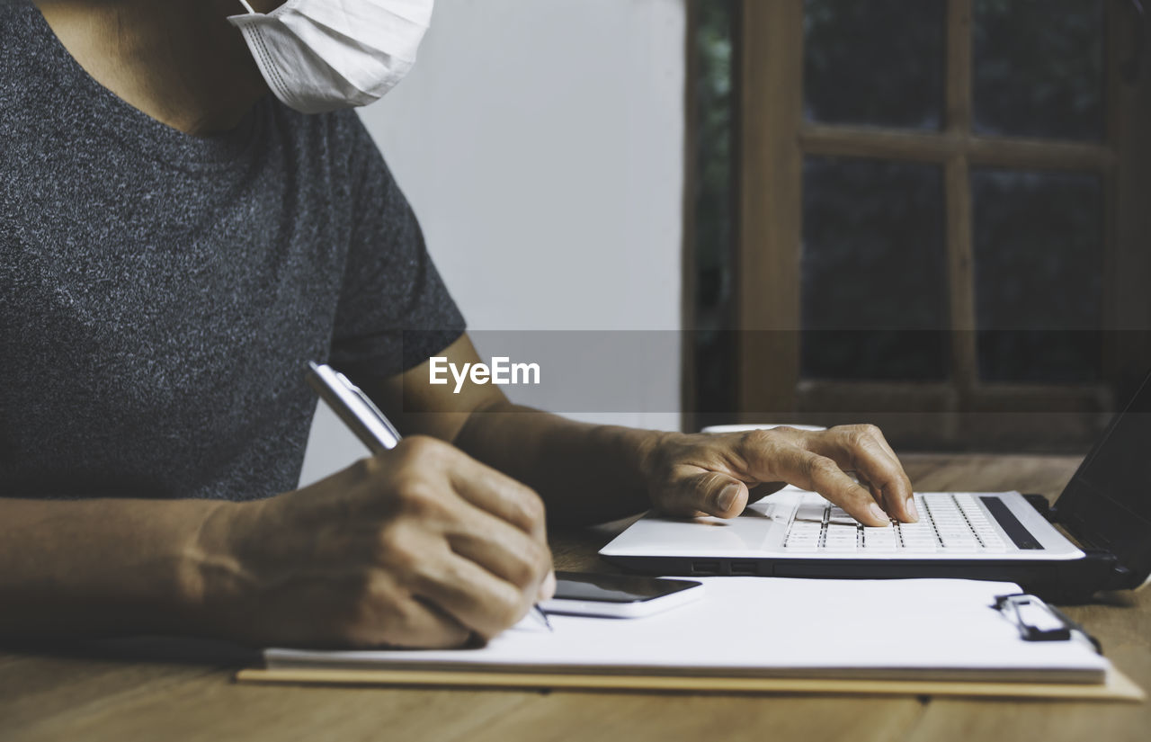 MIDSECTION OF MAN USING LAPTOP