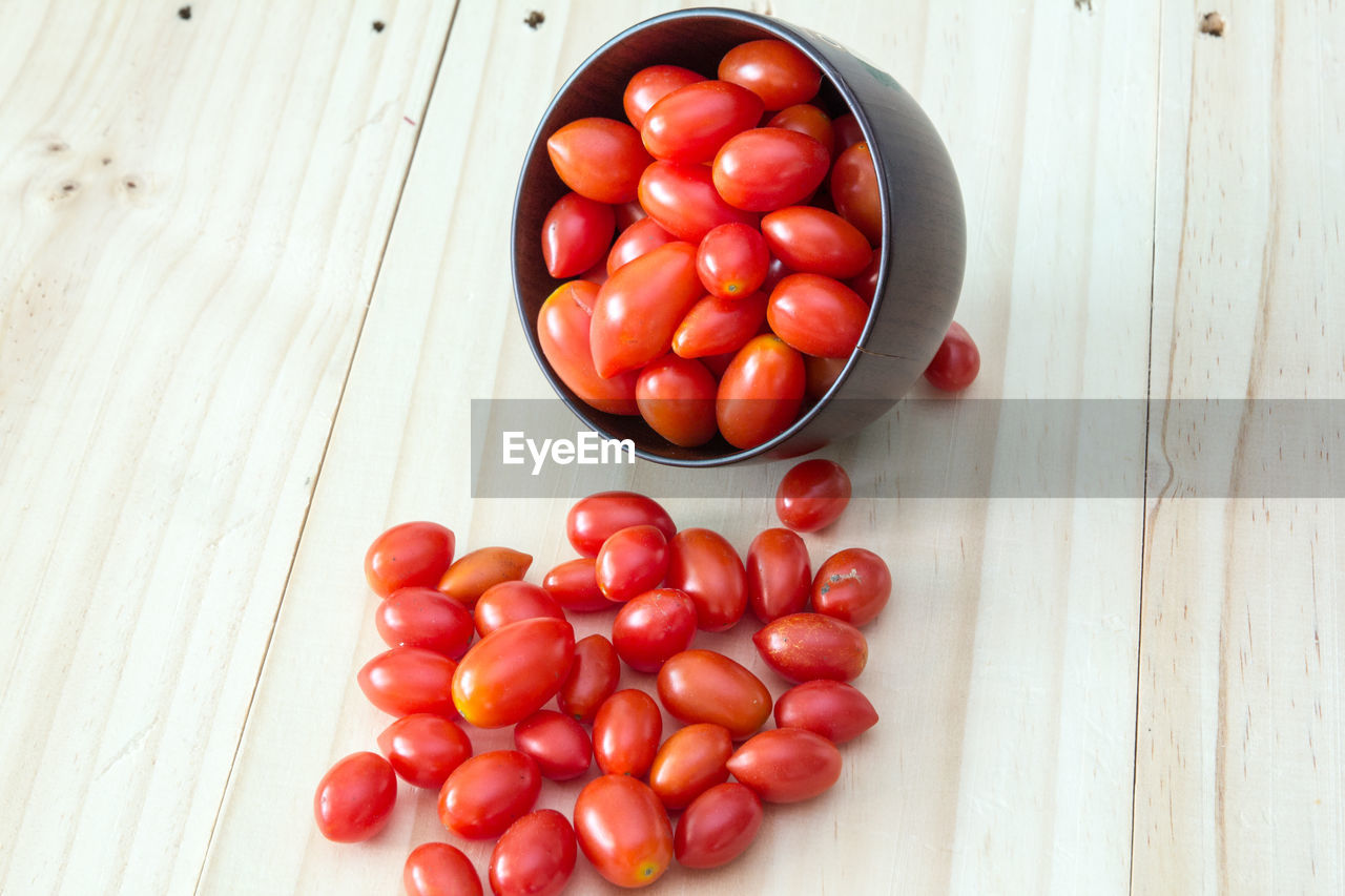 High angle view of cherry tomatoes in bowl on wooden table