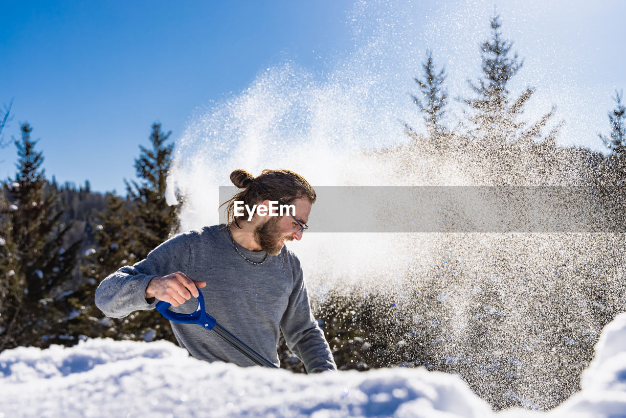 YOUNG MAN WITH SNOW ON TREE