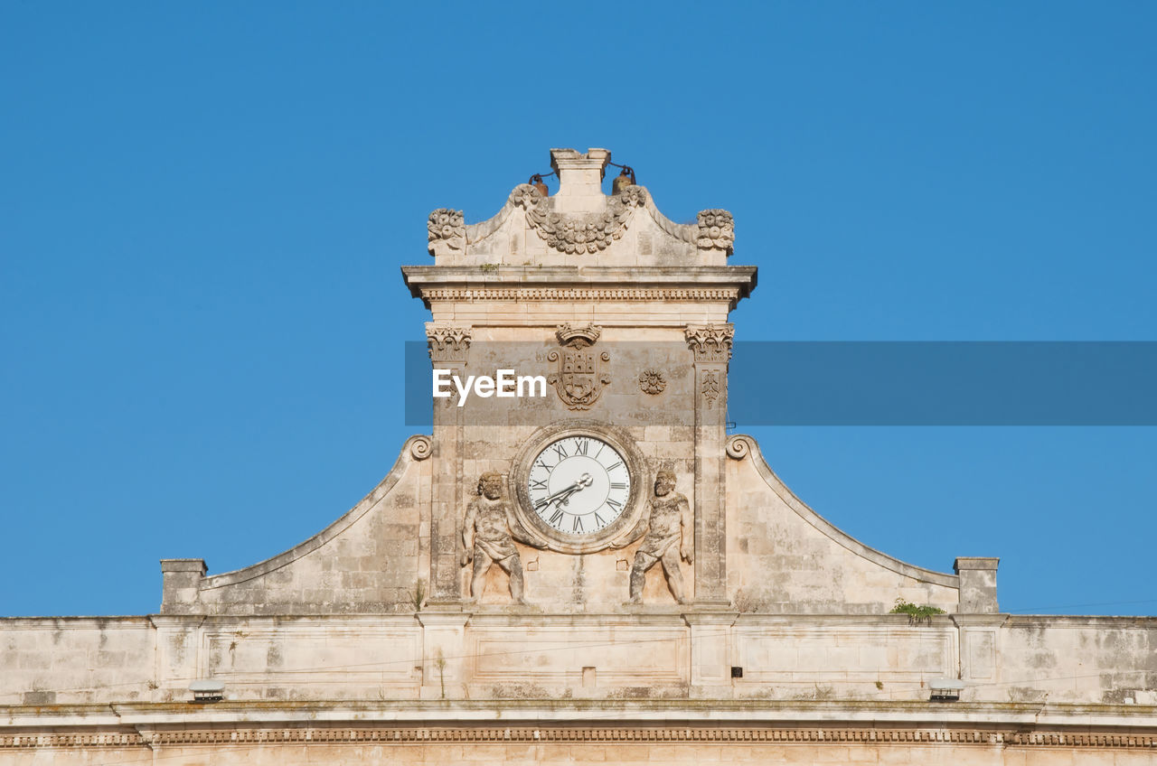 Low angle view of clock tower against blue sky in ostuni apulia
