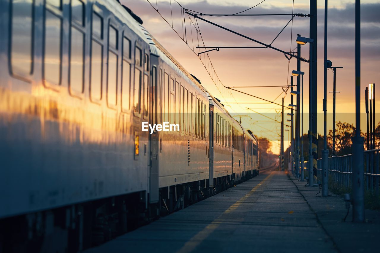 Railway at sunrise. passenger train leaving from railroad station.