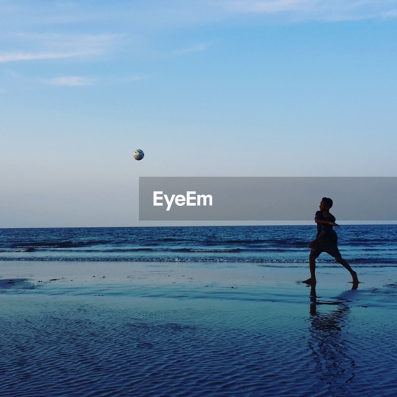 Boy playing soccer at beach