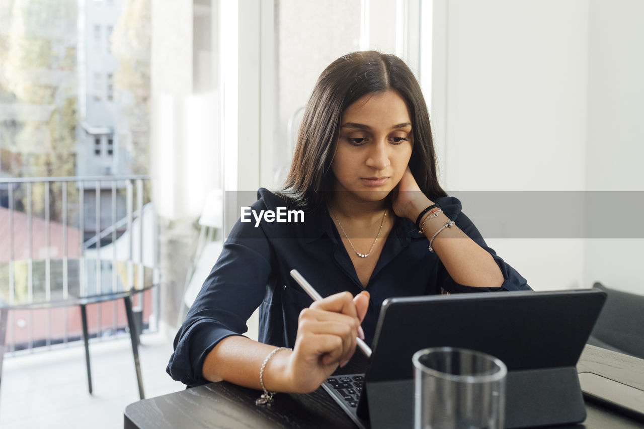 Woman studying through tablet pc on table at home