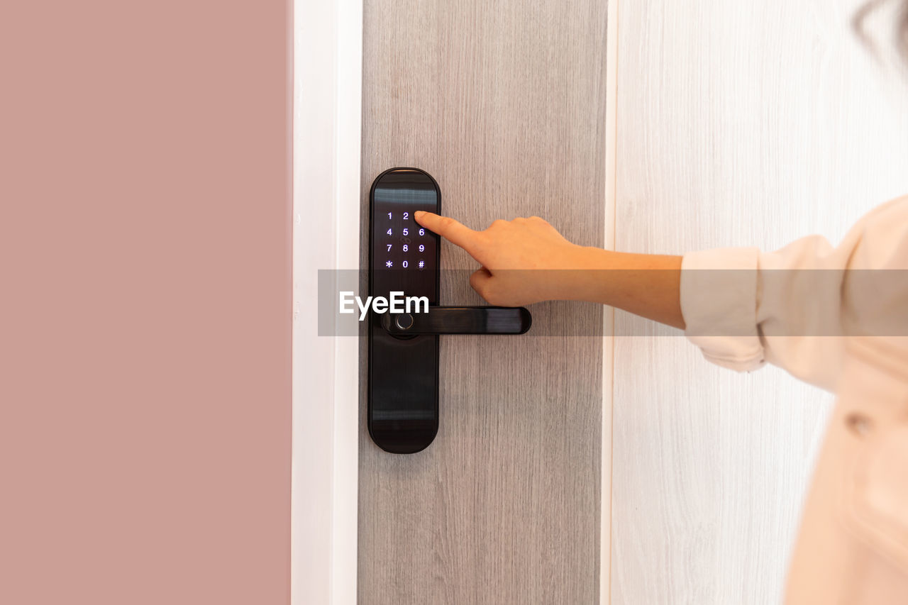 arm, adult, door, entrance, one person, women, technology, indoors, hand, lifestyles, home interior, domestic life, holding, female, accessibility, control, young adult, copy space, push button, lock, door handle, standing, knob, side view, pushing, clothing, doorknob