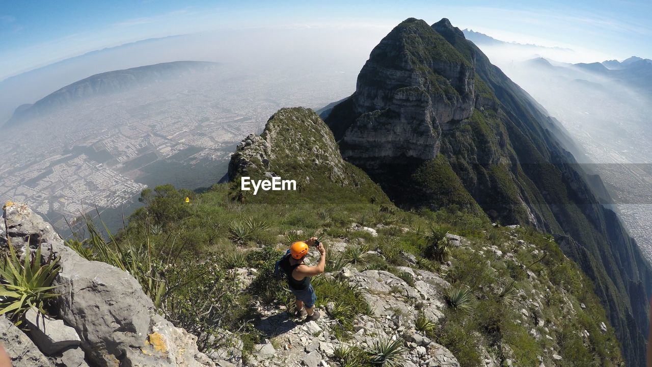 High angle view of man standing on cliff against mountains