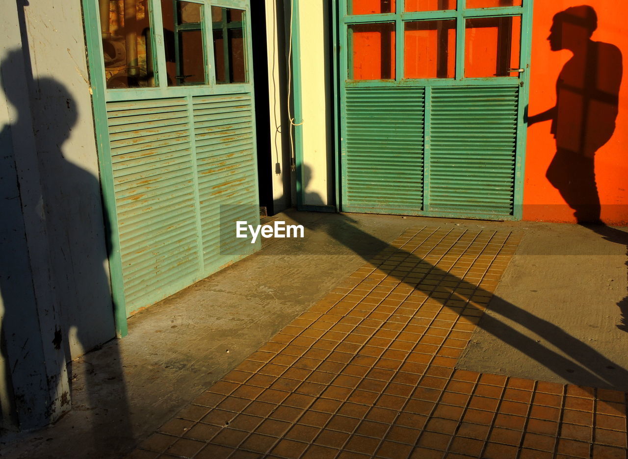 Shadow of person on footpath and door