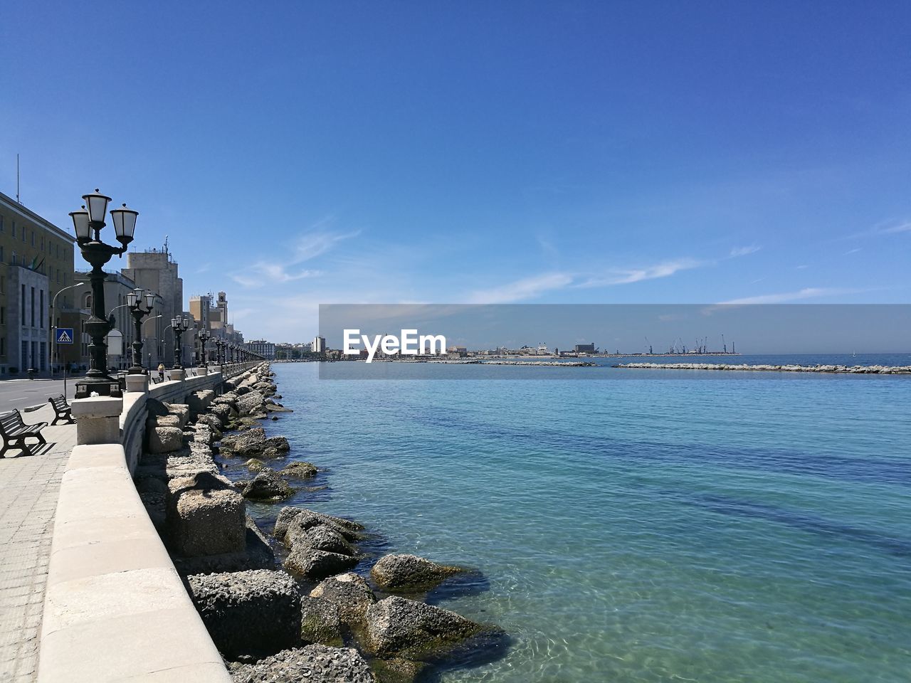 Scenic view of sea by city against blue sky