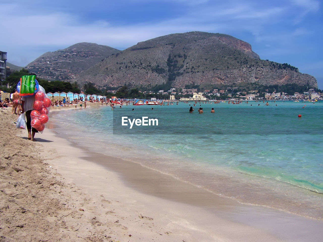 PEOPLE ON BEACH AGAINST MOUNTAIN RANGE