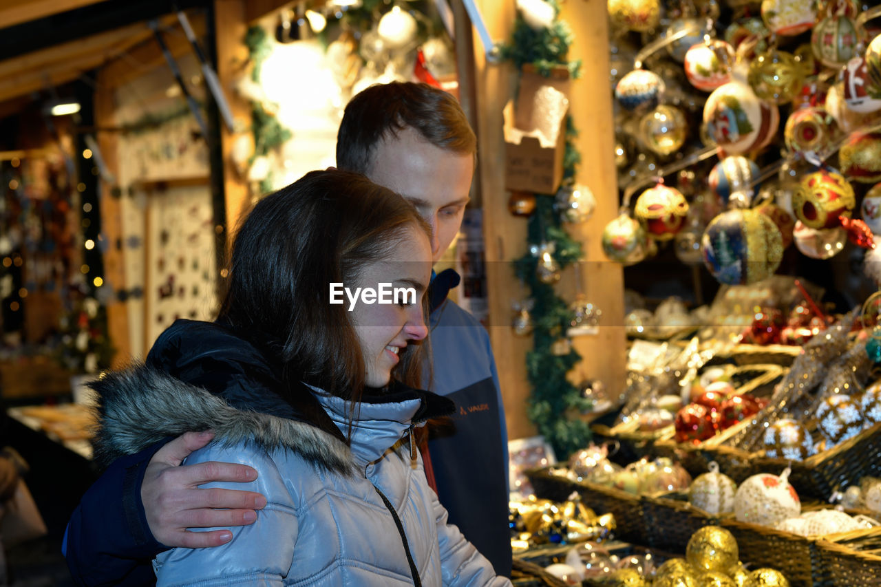 A young couple in love hugs at the christmas market.