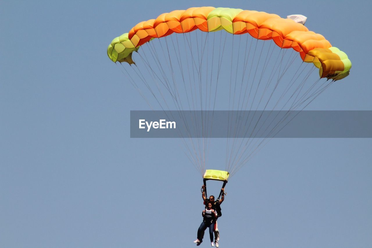 LOW ANGLE VIEW OF MAN PARAGLIDING AGAINST CLEAR SKY