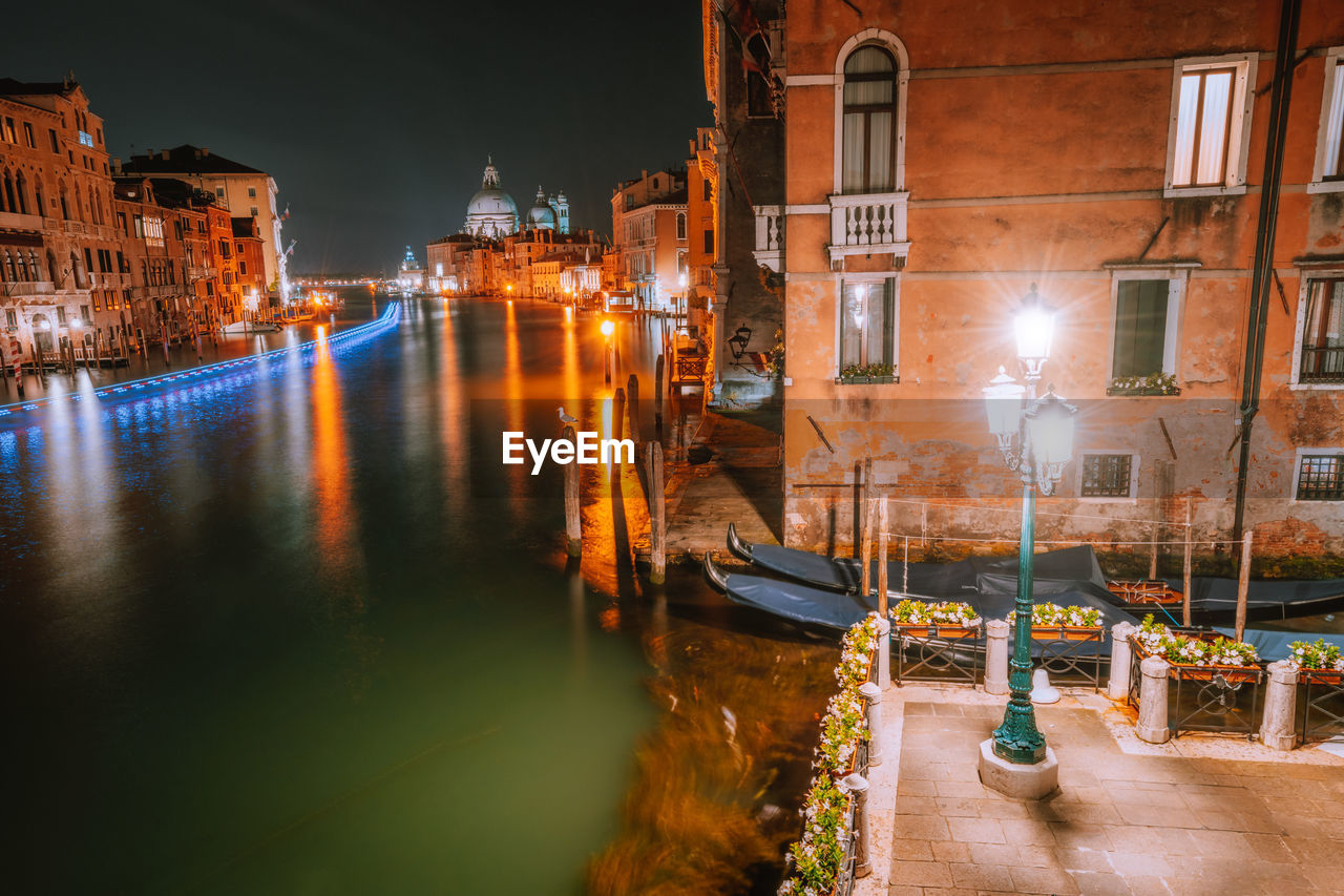 VIEW OF ILLUMINATED BUILDINGS AT WATERFRONT