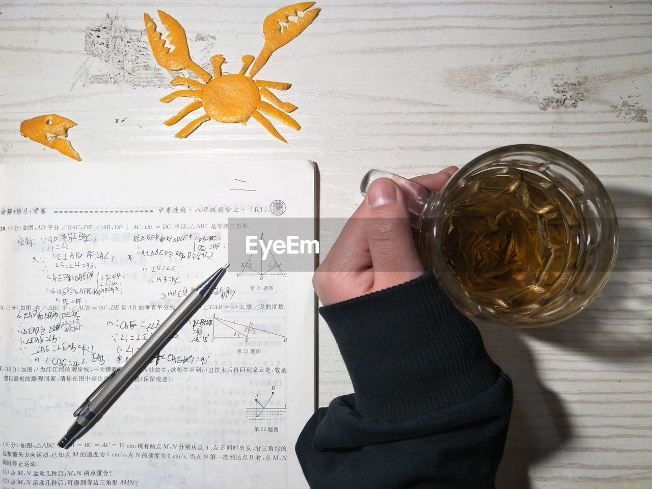 Cropped hand having drink while studying at table