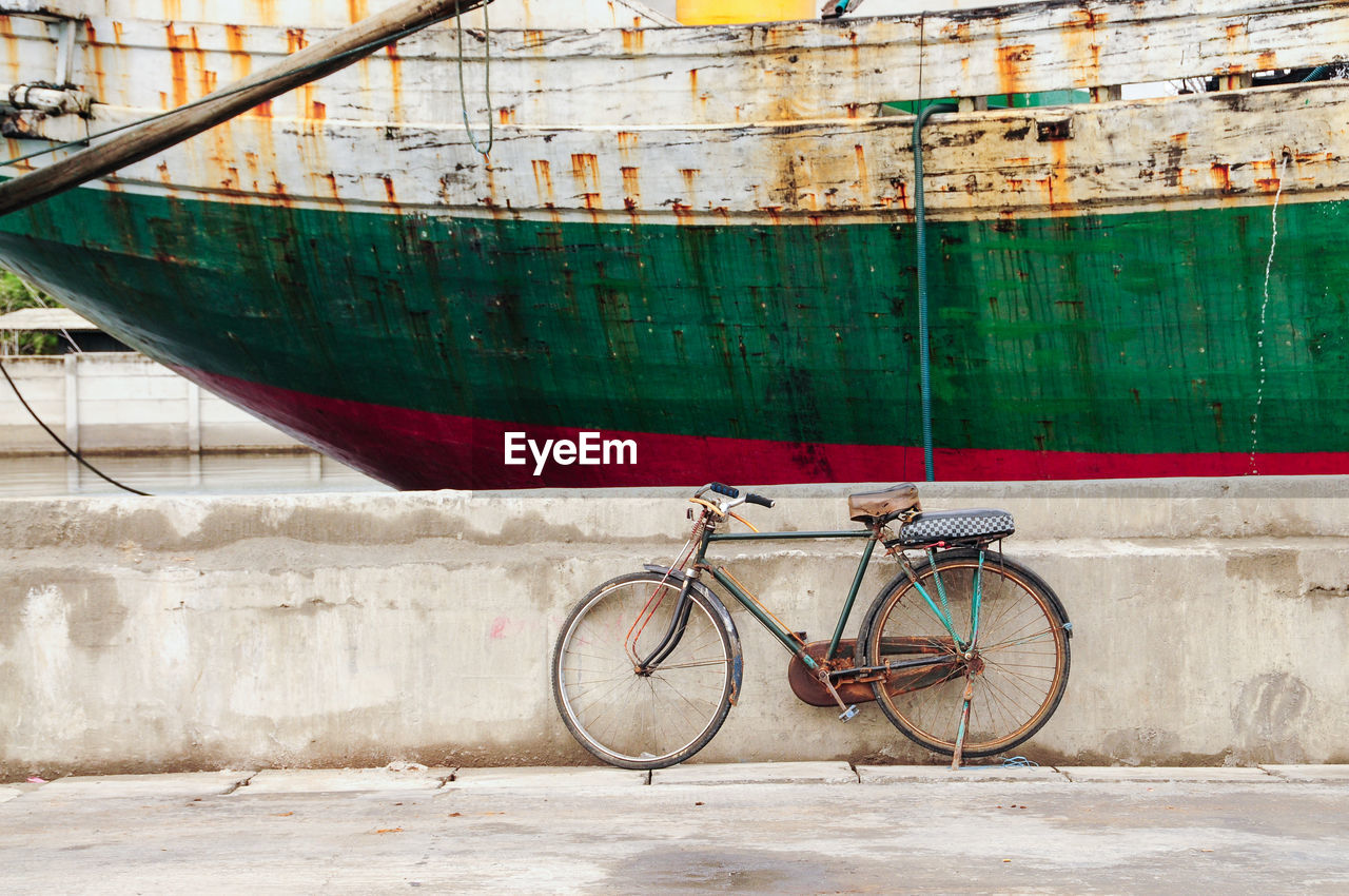 Bicycle leaning against wall by boat