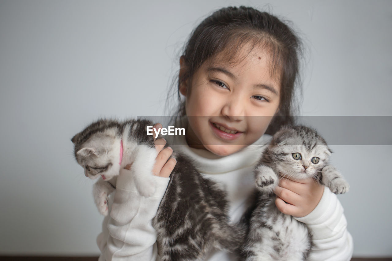 Portrait of cute girl holding two kittens
