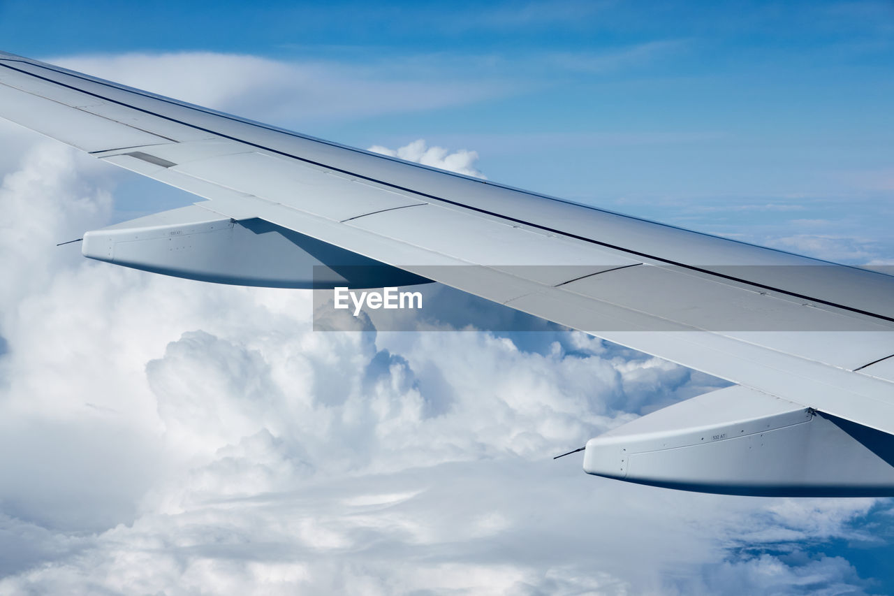 cropped image of airplane wing against blue sky