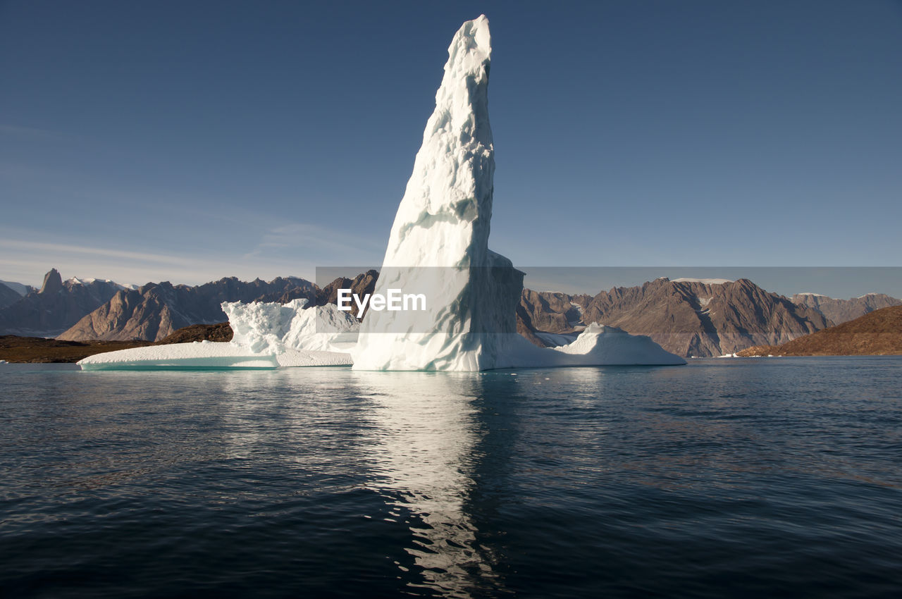 Scenic view of sea by snowcapped mountain against sky