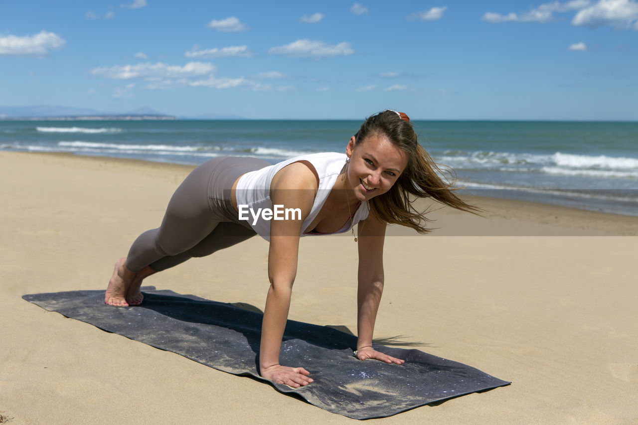 Sportswoman performing pilates exercises on the beach
