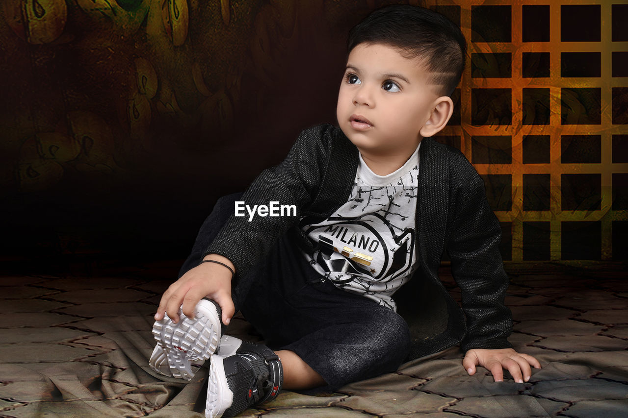 Portrait of cute boy sitting on floor at home