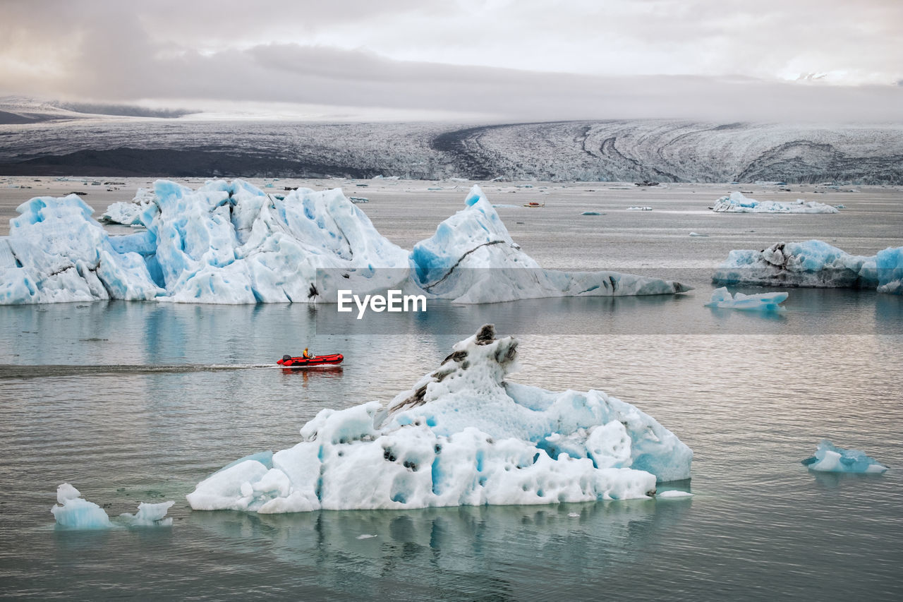 Icebergs in frozen sea against sky