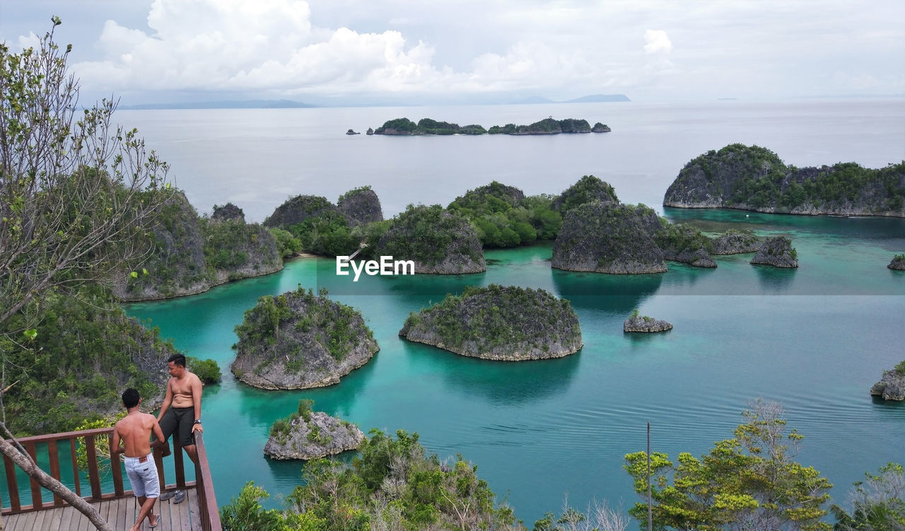 Panoramic view of people looking at sea against sky