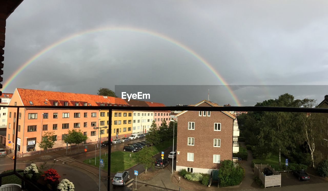 Rainbow in cloudy sky over houses seen from balcony