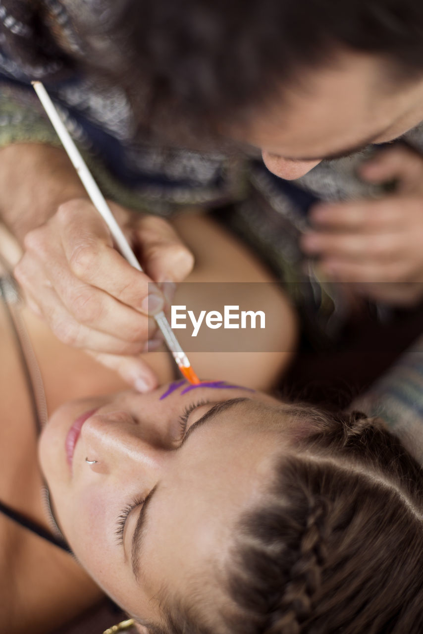 Overhead view of makeup artist painting model's face