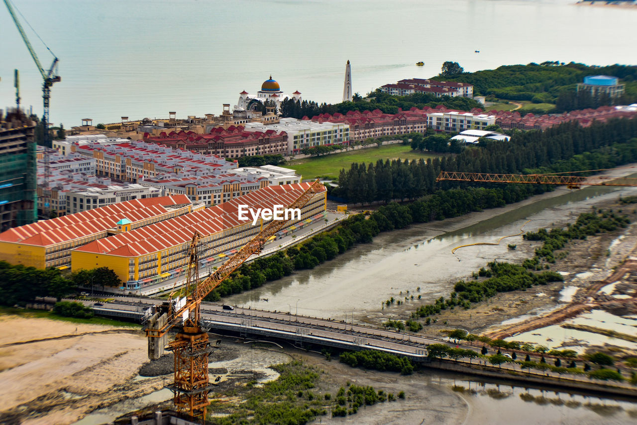 HIGH ANGLE VIEW OF RAILROAD TRACKS AMIDST CITY AGAINST SKY