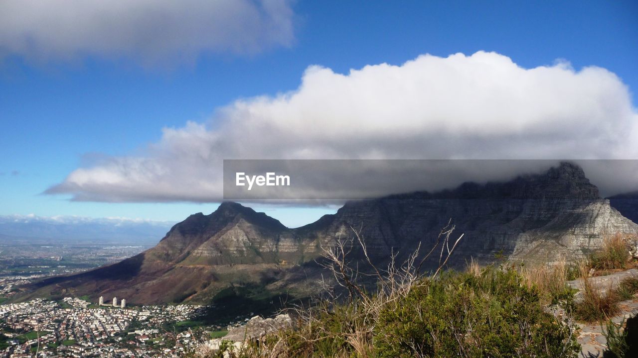 View of cloud over mountain peak and houses in foreground