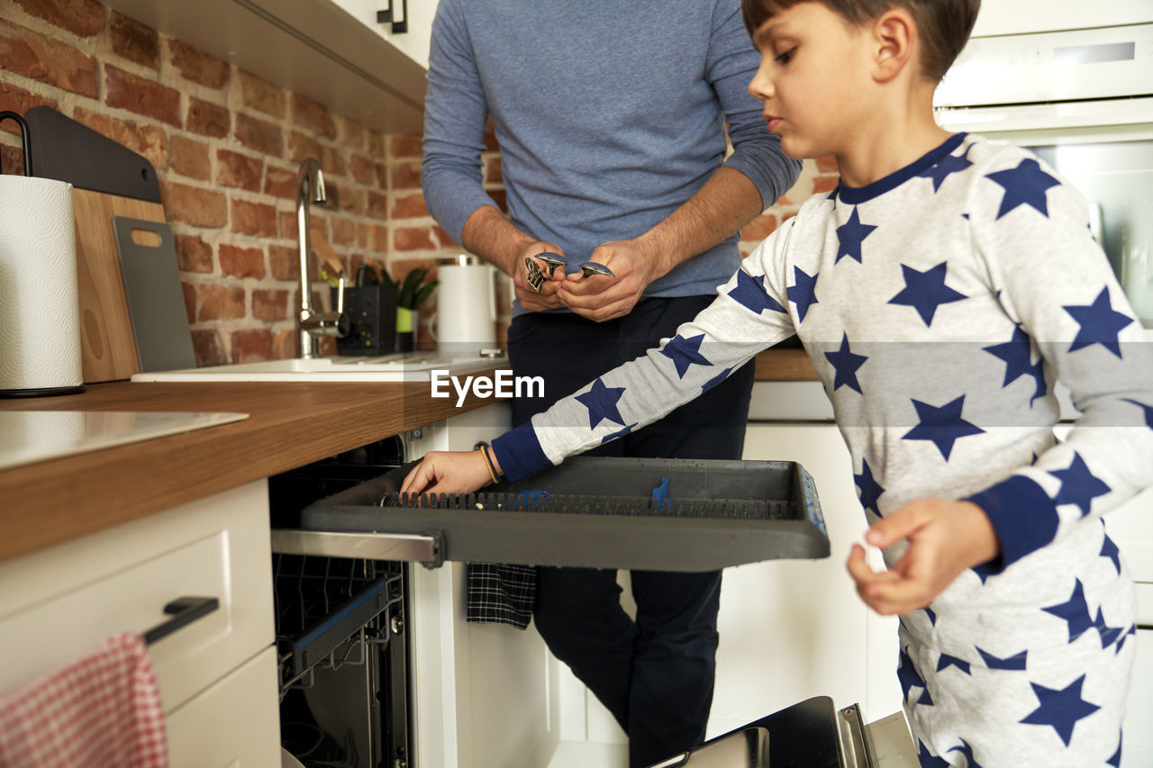 Boy arranging spoon in kitchen