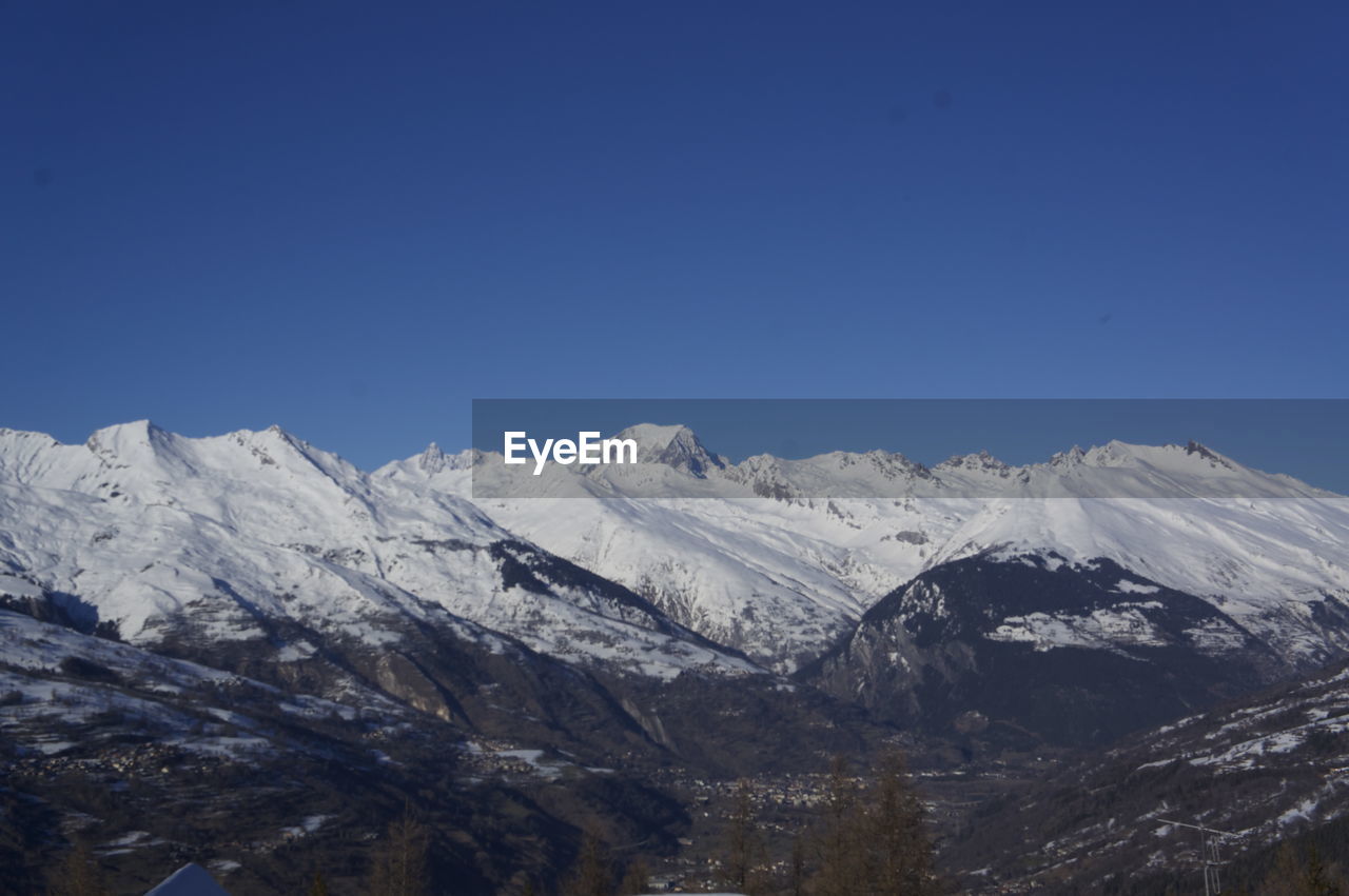 Scenic view of snowcapped mountains against clear blue sky