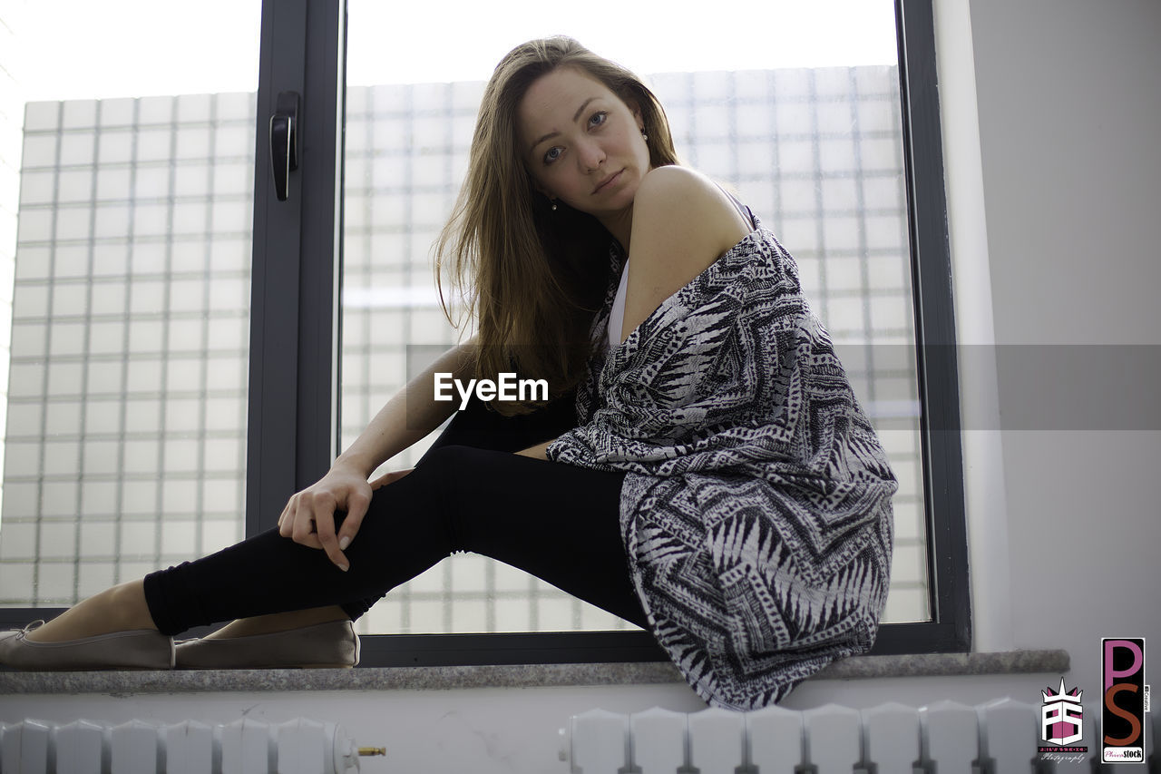 PORTRAIT OF YOUNG WOMAN STANDING OUTDOORS