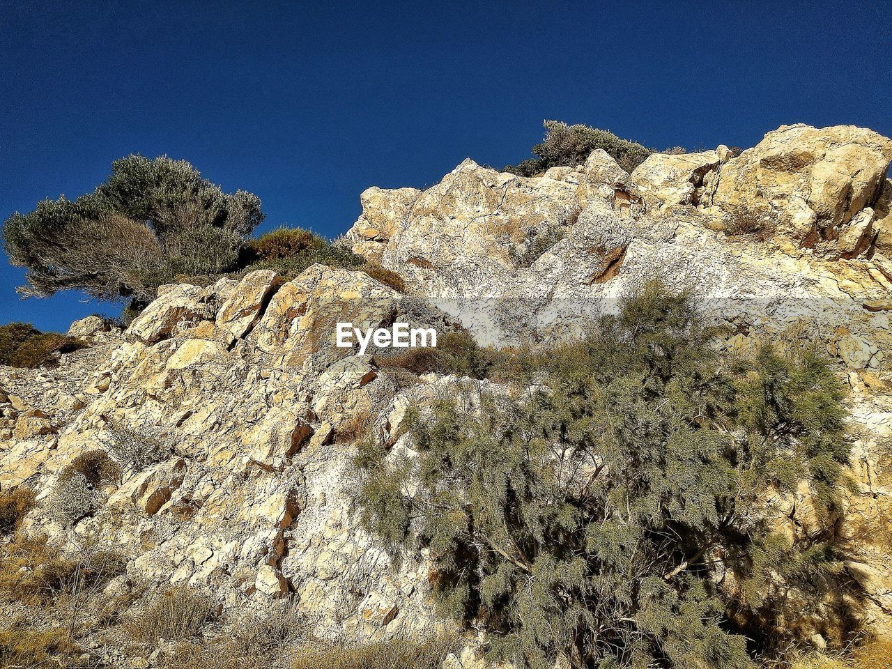 LOW ANGLE VIEW OF ROCK FORMATIONS AGAINST CLEAR BLUE SKY