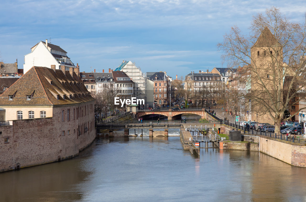 Bridge over river by buildings in city against sky