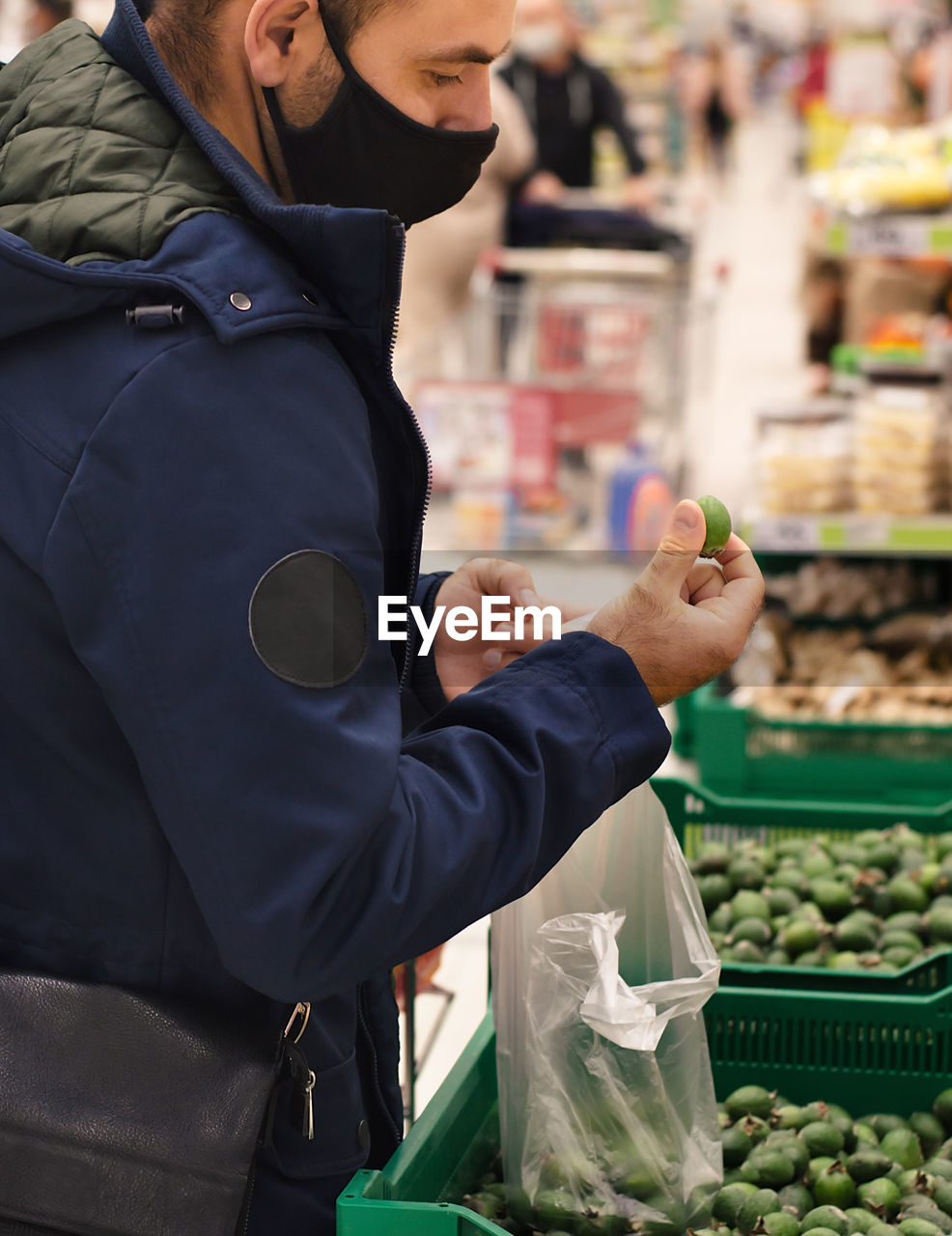 Midsection of man wearing mask standing at supermarket