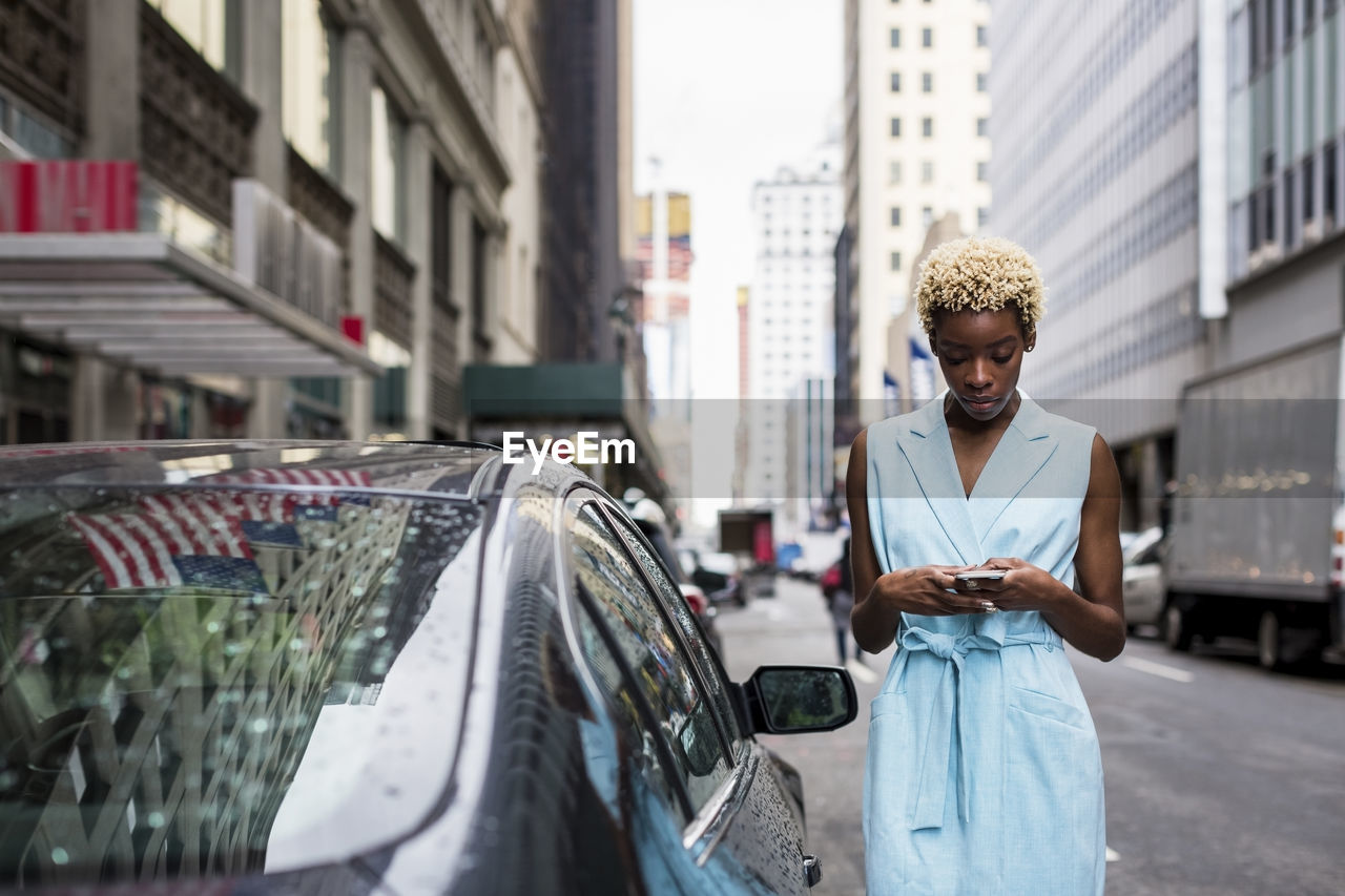 Usa, new york, young blonde african-american woman using smartphone