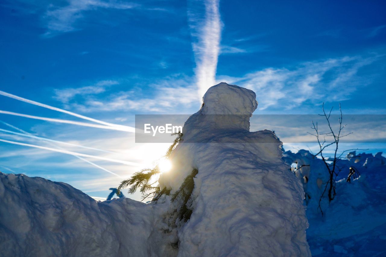 Low angle view of snow covered landscape against blue sky