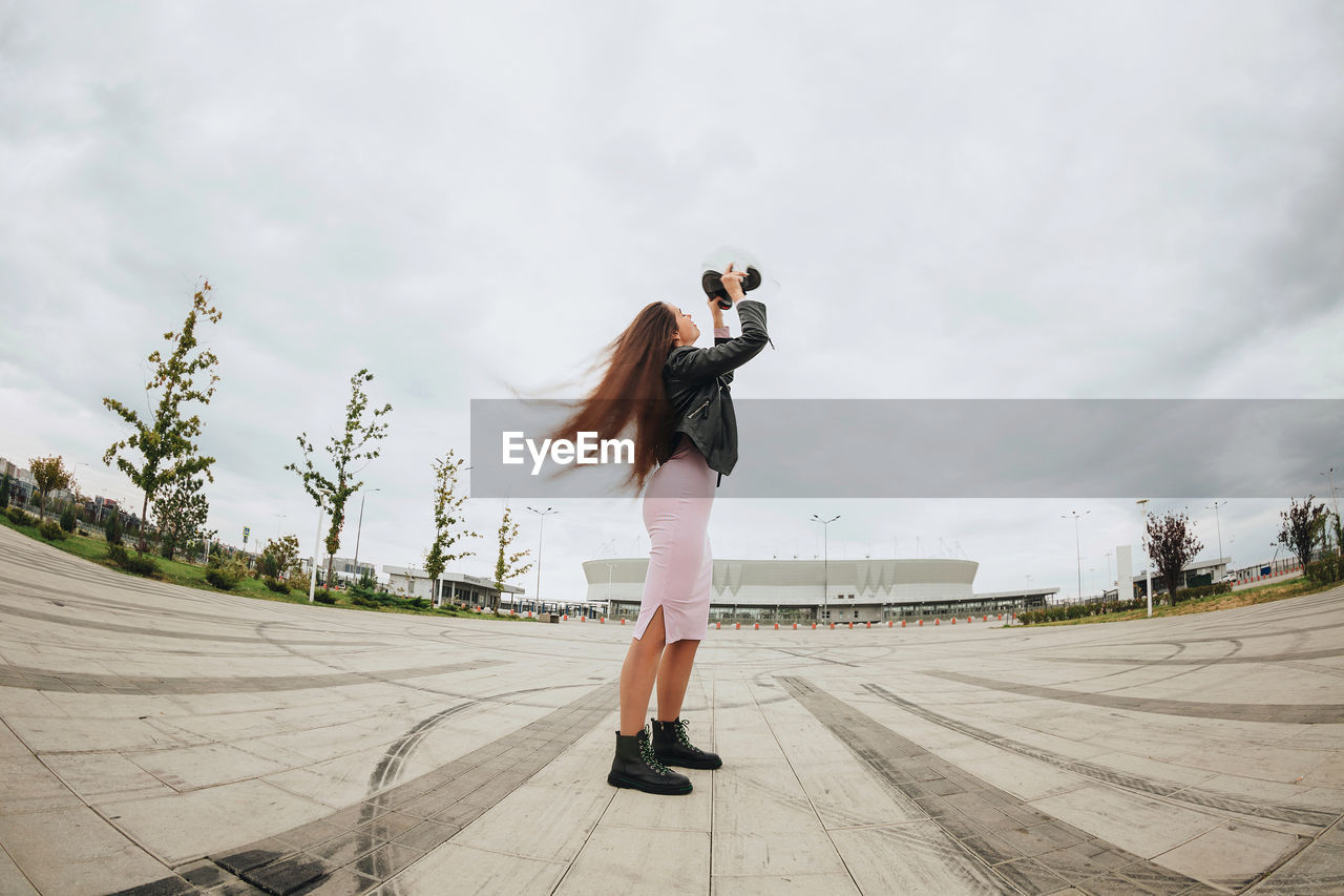 Rear view of woman walking on footpath against sky