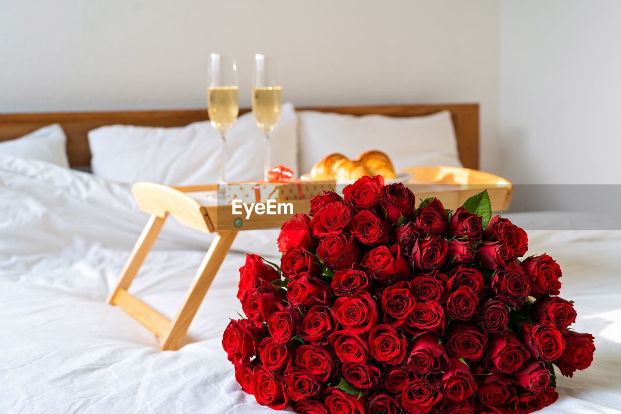 Celebrating saint valentine's day with bouquet of red roses, glass of champagne and croissants 