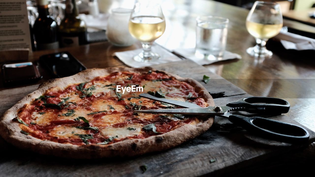 Close-up of pizza and scissor on table