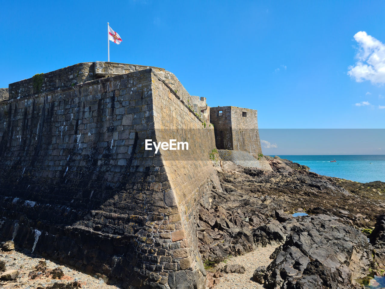 LOW ANGLE VIEW OF FORT AGAINST BLUE SEA