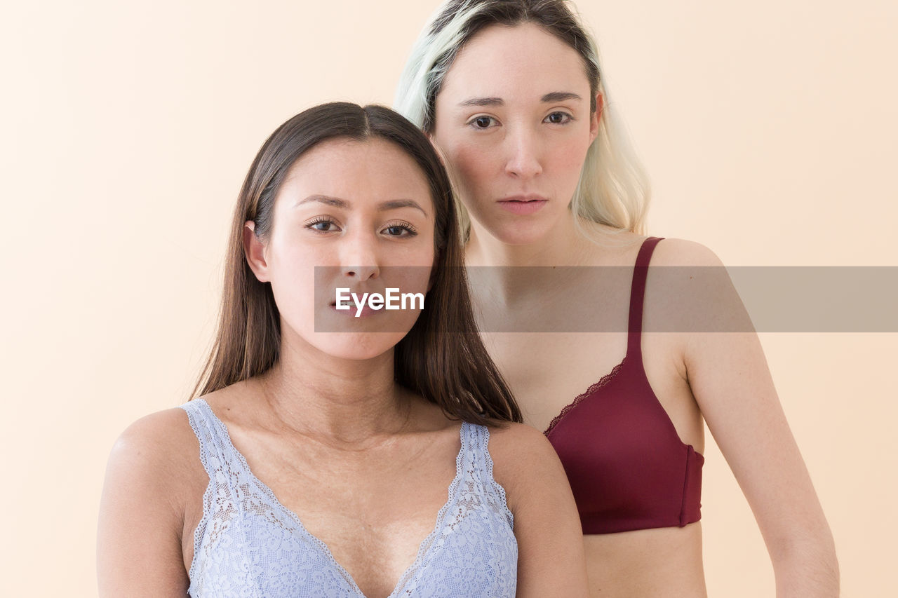 Portrait of young women wearing bikini against peach background