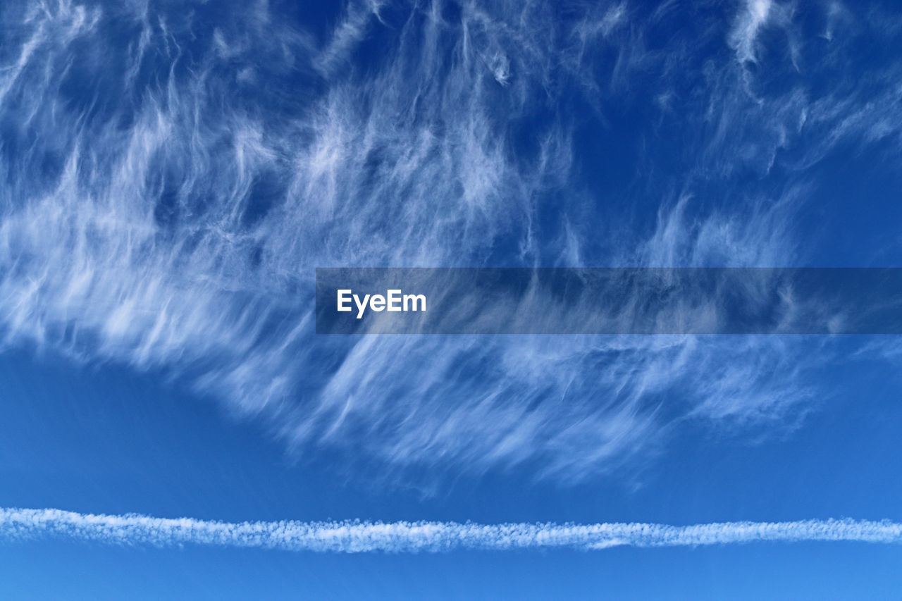 LOW ANGLE VIEW OF VAPOR TRAILS IN BLUE SKY